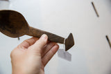 The carved handle and unique triangular pommel of a vintage wooden spoon.