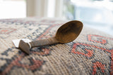 Profile view of a vintage wooden spoon showing the deep bowl and carved handle.