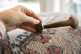 Vintage African wooden spoon held to show its scale and dark, aged patina.
