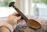 A vintage African spoon held in hand, displaying its aged wood and hand-carved details.
