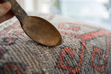 Close-up on the rustic patina and warm wood grain of a vintage African spoon.