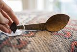 Carved geometric details on the dark wood handle of a vintage African spoon.