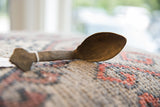 The aged wooden texture and hand-carved profile of a vintage African spoon.