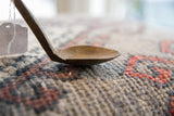Aged texture and shallow, hand-carved profile of the vintage spoon's bowl.