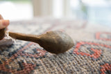 Side profile of the hand-carved wooden spoon, highlighting its weathered, rustic texture.