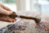 Vintage African wooden spoon held in hand to show its scale and dark, rustic patina.
