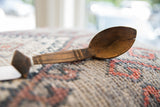 Aged patina, carved handle details, and a split tip on a vintage African wooden spoon.