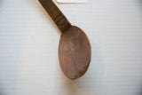 Hand-carved geometric details on the handle of an aged African wooden spoon.