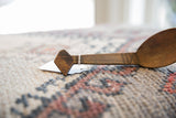 Carved diamond finial and etched details on the handle of an aged wooden spoon.