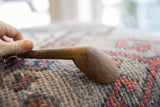 The hand-carved form and deep wood grain of a vintage African spoon.