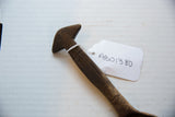Top of the vintage wooden spoon handle showing carved lines and attached paper tag.