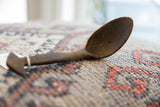 Profile view of the vintage wooden spoon, highlighting its deep bowl and dark, aged wood.