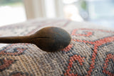 A close view of the aged, cracked texture on the dark wooden spoon's bowl.