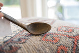 Detail showing the weathered texture and aged imperfections of the vintage spoon's bowl.
