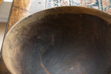 Aged texture, visible crack, and hand-stitched repair on the rim of a vintage wooden bowl.