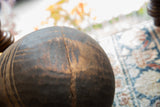 A prominent crack and weathered texture on the vintage wooden bowl's surface.