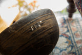 Angled view of the vintage wooden bowl's exterior, showing fine carved lines and a repair.