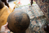 Vintage African wooden bowl held to display its dark, worn surface and aged character.