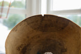 Vintage African wooden bowl close-up showing rim crack and aged wood texture.
