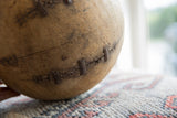 Vintage African wooden bowl detail showing aged wood texture, prominent cracks, and staple-like metal repairs.