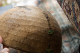 Visible repairs on the aged African wooden bowl, with metal stitching and green plates.