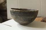 Close-up of the vintage African wooden bowl's rim, showing a storied domestic repair.
