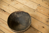 The worn, patinated interior of a vintage handmade wooden bowl viewed from above.