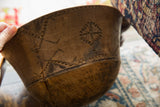Vintage African wooden bowl with carved geometric patterns and visible ancient mends.