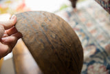 A hand holds the side of the vintage wooden bowl, highlighting its rustic, carved exterior.