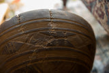 Wavy metal staple repairs across a crack on the carved surface of a vintage bowl.