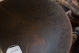 The dark, aged surface inside a handmade wooden bowl showing textural character cracks.
