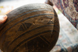 Close-up view of hand-carved geometric line work on a vintage dark wood bowl.