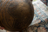 Close-up of the hand-carved geometric patterns on the aged, textured wooden bowl.
