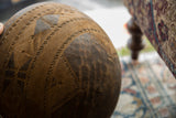 Close-up of vintage African wooden bowl, highlighting hand-carved geometric patterns and natural wood texture.