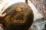 Dark wooden bowl detail with light carved geometric designs and integrated repairs.