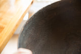 Vintage African wooden bowl interior, showing dark textured grain and visible crack.