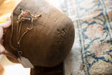 Textured side of vintage African wooden bowl, featuring carved patterns and rope.
