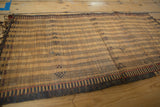 Golden straw texture with woven dark linear and geometric patterns on a vintage Tuareg mat.