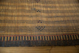 Handwoven straw texture of a vintage Tuareg mat with dark binding and red line.