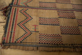 Handwoven straw texture with striking red and deep blue geometric patterns on the Tuareg mat.
