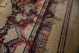 Intricate handwoven straw texture of a vintage Tuareg mat with red and black tattered threads.