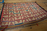Vintage Tuareg straw mat with a geometric grid of red, blue, and black pyramid designs.