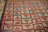 Detailed view of a handwoven Tuareg mat's straw weave with red, blue, and black geometric designs.