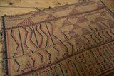 Handwoven straw texture of a vintage Tuareg mat, featuring geometric red, black, and turquoise designs.