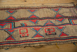 Handwoven straw Tuareg mat texture with vibrant red and blue geometric patterns.