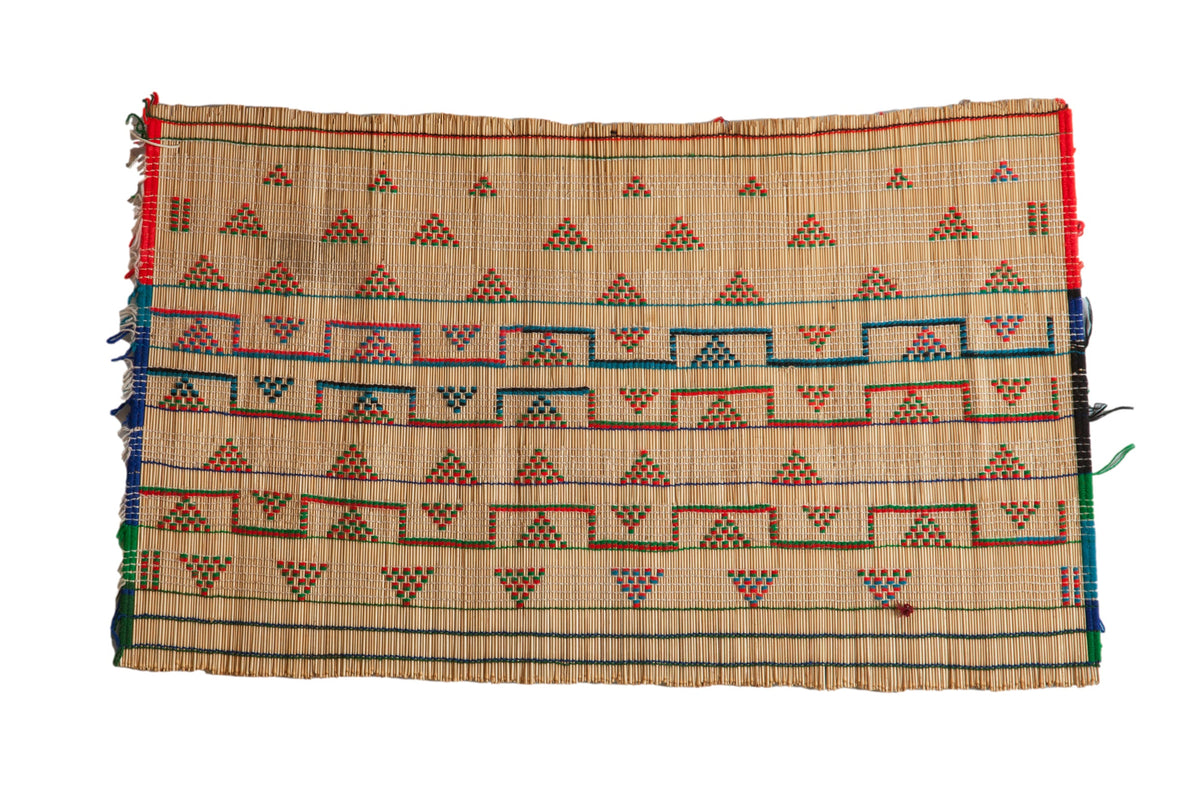 Vintage Tuareg straw mat with handwoven geometric patterns in red, green, and blue.