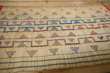 Woven straw texture and geometric designs in red, green, and blue on a Tuareg mat.