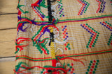 Detail of the rustic, colorful yarn stitching on a handwoven Tuareg straw mat.