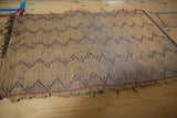 Handwoven straw texture with dark zigzag pattern and red edge on a vintage Tuareg mat.