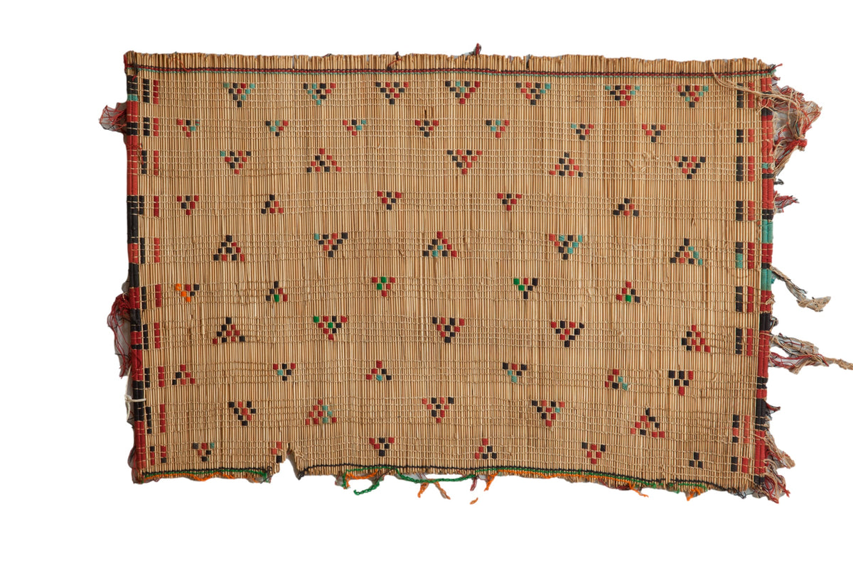 Vintage Tuareg straw mat with geometric triangle patterns in red, black, and teal.